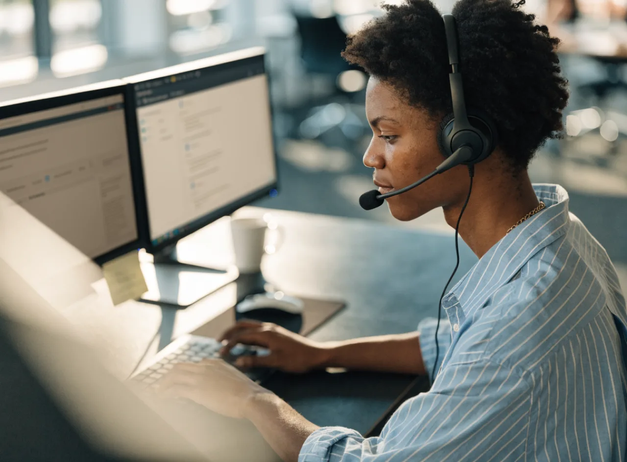 Front desk staff member working at a computer with a headset.